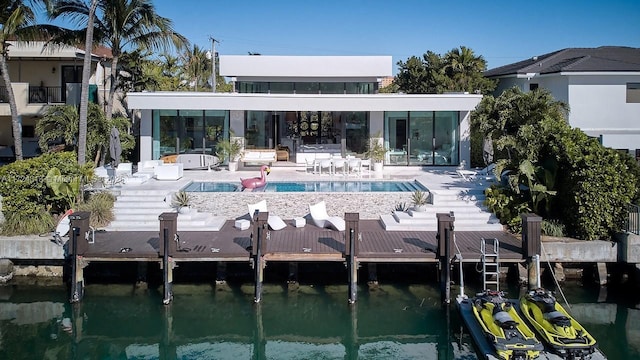 rear view of property with a water view, a patio, and a pool with hot tub