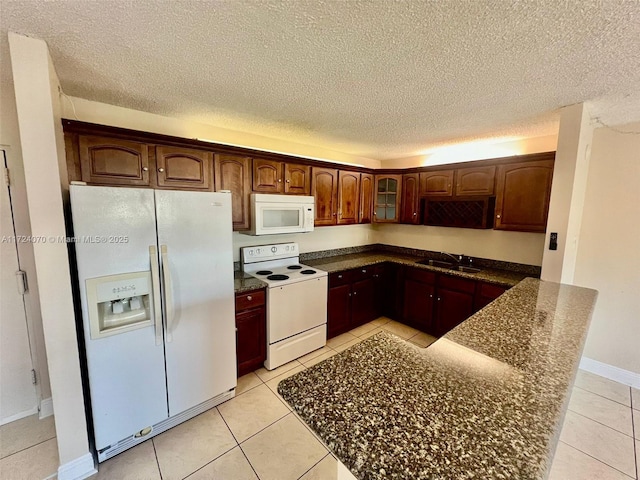 kitchen featuring dark brown cabinets, sink, light tile patterned flooring, and white appliances