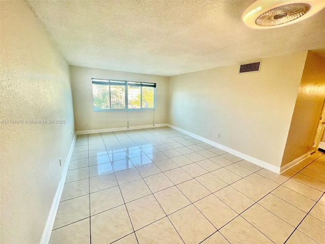 spare room featuring light tile patterned floors and a textured ceiling