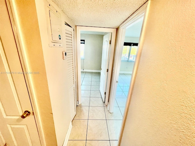 corridor featuring light tile patterned floors and a textured ceiling