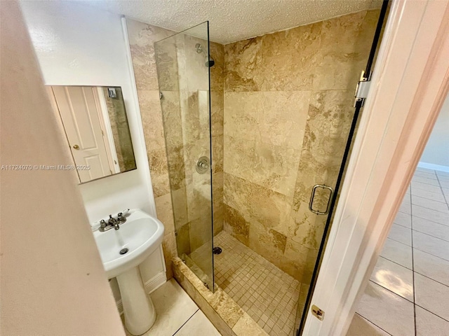 bathroom with a textured ceiling, tile patterned flooring, and an enclosed shower