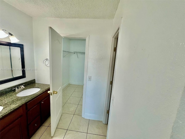 bathroom with tile patterned flooring, vanity, and a textured ceiling