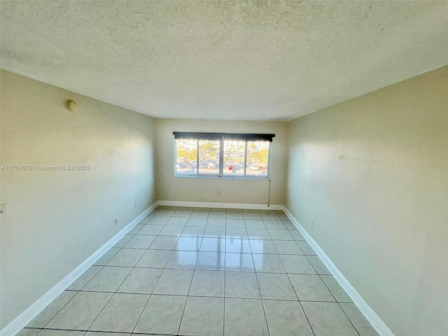 empty room featuring light tile patterned floors and a textured ceiling