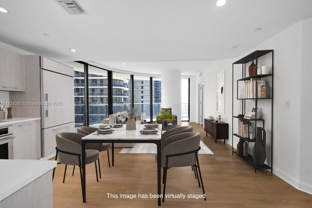 kitchen with floor to ceiling windows, oven, sink, light hardwood / wood-style flooring, and white cabinetry