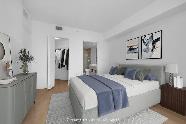 bedroom with a spacious closet, light hardwood / wood-style floors, a closet, and ensuite bathroom