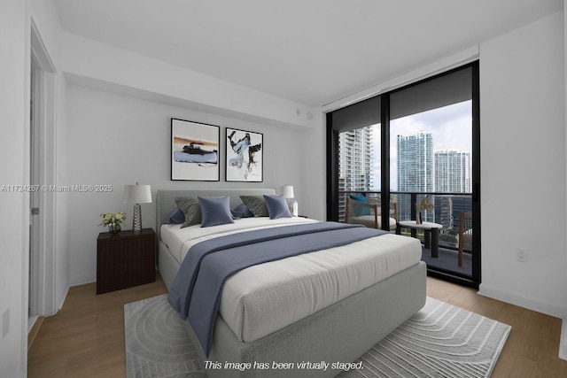 bedroom featuring floor to ceiling windows, light hardwood / wood-style flooring, and access to outside