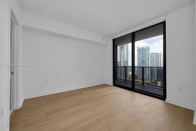 empty room with floor to ceiling windows and light wood-type flooring