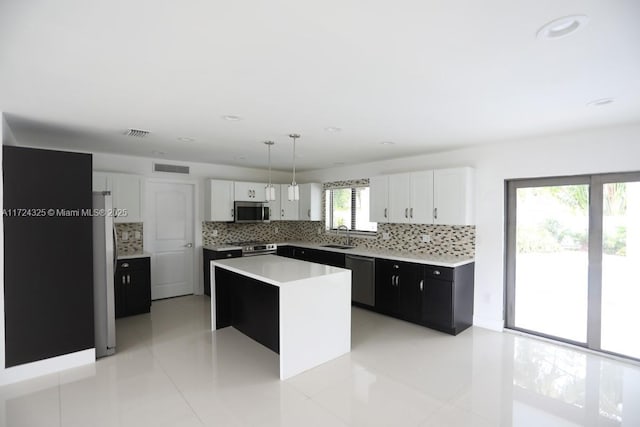 kitchen with pendant lighting, a wealth of natural light, a center island, white cabinetry, and stainless steel appliances