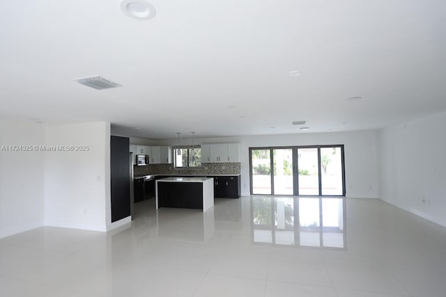 kitchen featuring light tile patterned flooring, a kitchen island, and backsplash