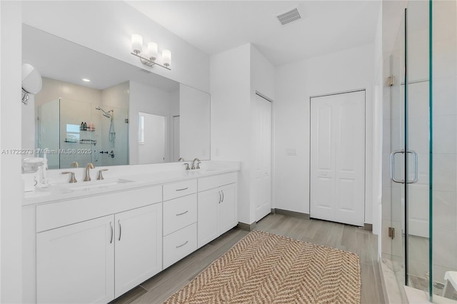 bathroom featuring hardwood / wood-style floors, vanity, and a shower with door