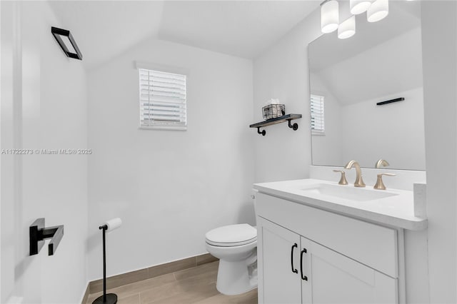 bathroom featuring a wealth of natural light, vanity, vaulted ceiling, and toilet