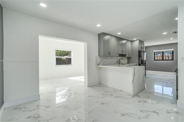 kitchen featuring backsplash, gray cabinets, and kitchen peninsula