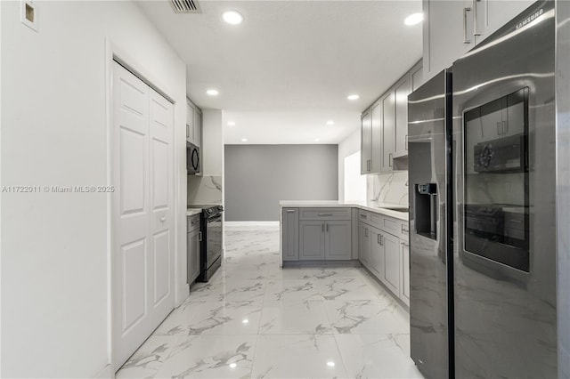 kitchen featuring backsplash, gray cabinetry, and black appliances