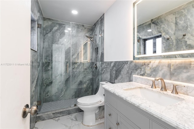 bathroom with vanity, toilet, tile walls, and a shower with shower door