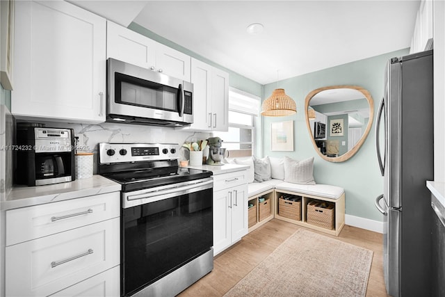 kitchen featuring appliances with stainless steel finishes, white cabinetry, backsplash, and light wood finished floors