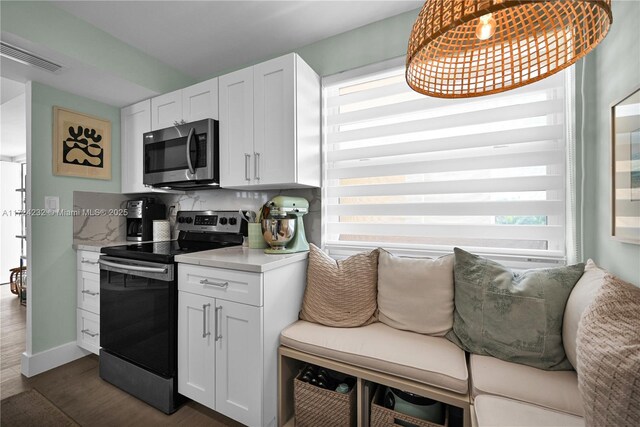 kitchen with dark hardwood / wood-style flooring, hanging light fixtures, stainless steel appliances, and white cabinets