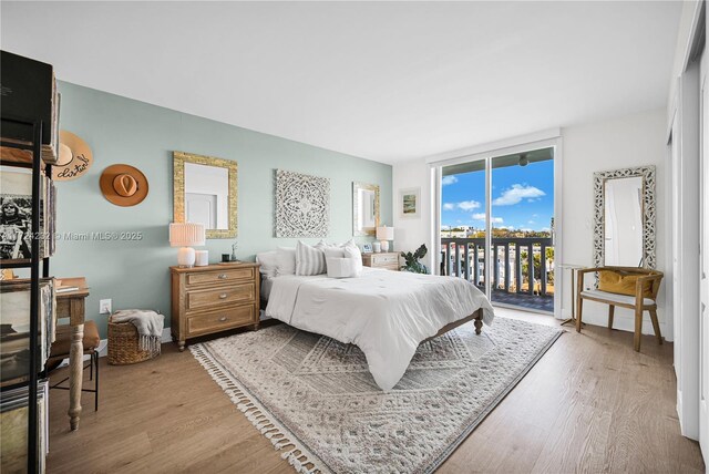 bedroom featuring access to exterior, expansive windows, and light wood-type flooring