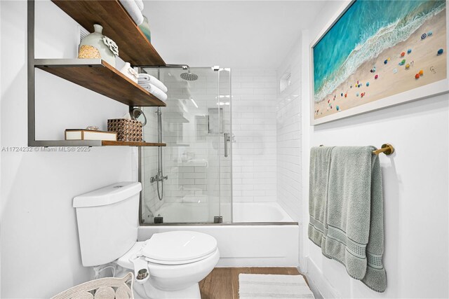 bathroom featuring hardwood / wood-style floors, shower / bath combination with glass door, and toilet