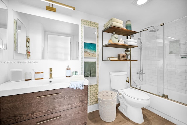 full bathroom featuring vanity, wood-type flooring, toilet, and combined bath / shower with glass door