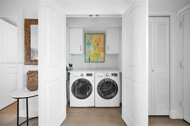 laundry room featuring light wood-style flooring, washer and clothes dryer, and cabinet space