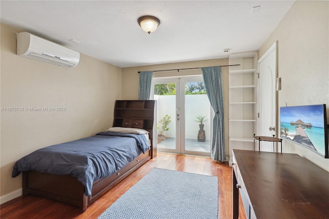 bedroom featuring a wall mounted air conditioner, french doors, access to exterior, and hardwood / wood-style flooring