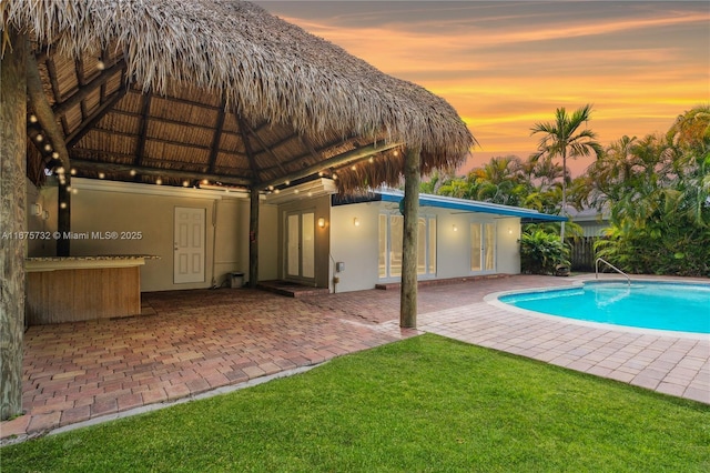 pool at dusk with a gazebo and a patio