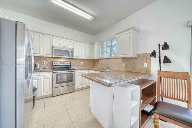 kitchen with white cabinets, sink, kitchen peninsula, and stainless steel appliances