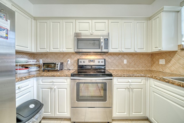 kitchen with decorative backsplash, stainless steel appliances, white cabinetry, and stone countertops