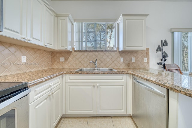 kitchen with sink, stainless steel appliances, light tile patterned floors, backsplash, and white cabinets