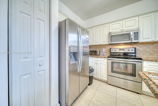 kitchen with tasteful backsplash, white cabinets, light tile patterned floors, and appliances with stainless steel finishes