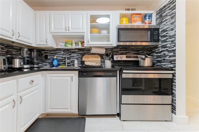 kitchen with backsplash, white cabinets, light tile patterned floors, and appliances with stainless steel finishes