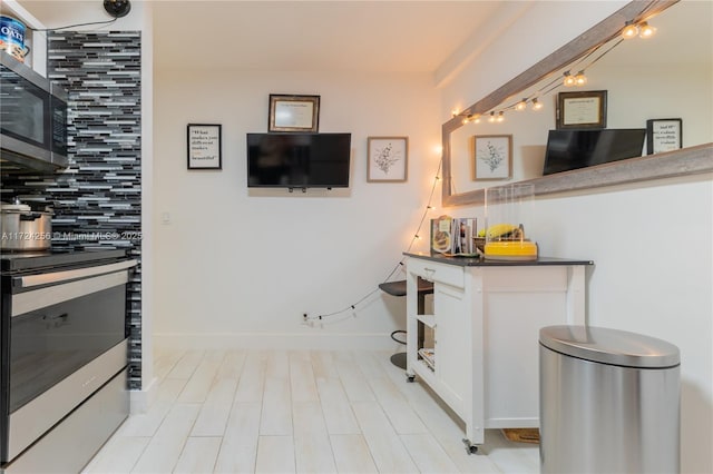 kitchen featuring decorative backsplash, white cabinets, and appliances with stainless steel finishes