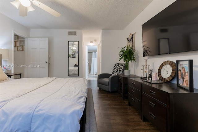 bedroom featuring ensuite bath, ceiling fan, dark hardwood / wood-style floors, and a textured ceiling