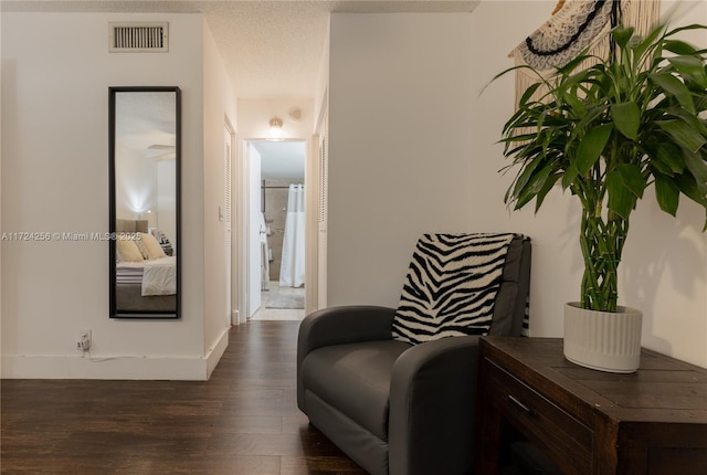 sitting room with dark wood-type flooring and a textured ceiling