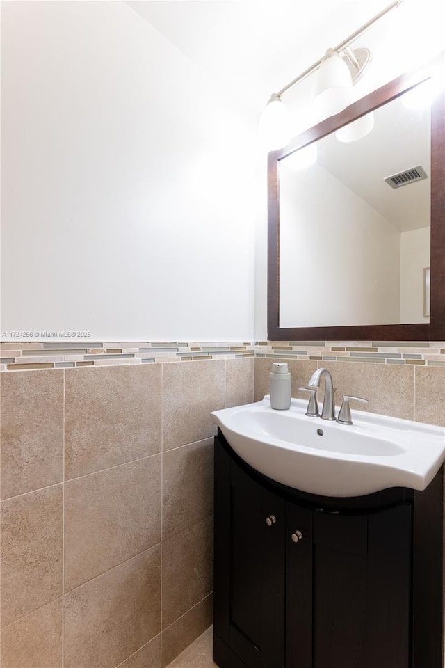 bathroom featuring vanity and tile walls