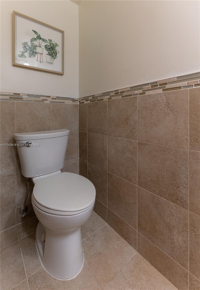 bathroom featuring tile patterned flooring, toilet, and tile walls