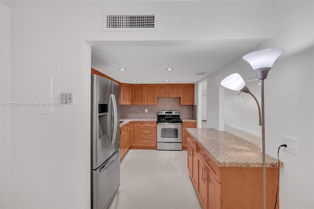 20291 NE 30th Ave Unit 108, Aventura, FL 33180 - kitchen featuring light tile patterned flooring, light stone countertops, appliances with stainless steel finishes, visible vents, and decorative backsplash