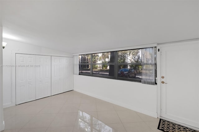 unfurnished bedroom featuring vaulted ceiling, light tile patterned floors, and a closet