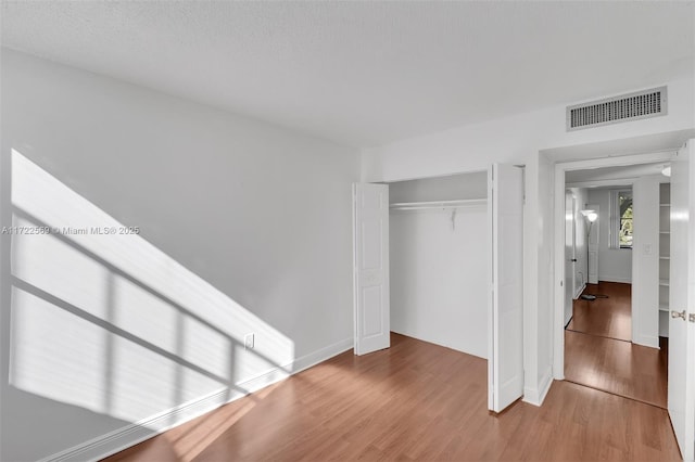 unfurnished bedroom with hardwood / wood-style floors and a closet