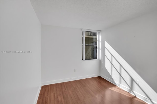 spare room featuring wood-type flooring and a textured ceiling