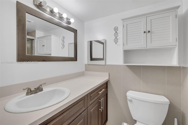 bathroom with vanity, tile walls, and toilet