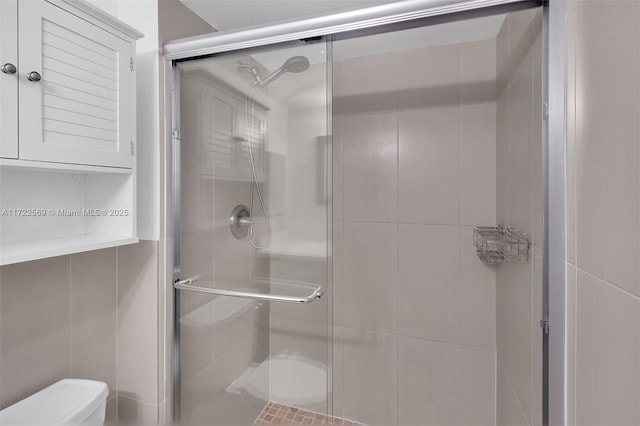 bathroom with walk in shower, toilet, and tile walls