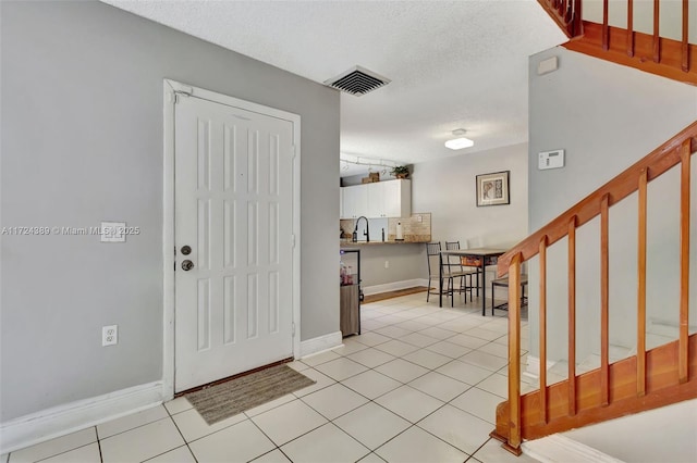 tiled foyer featuring a textured ceiling and sink