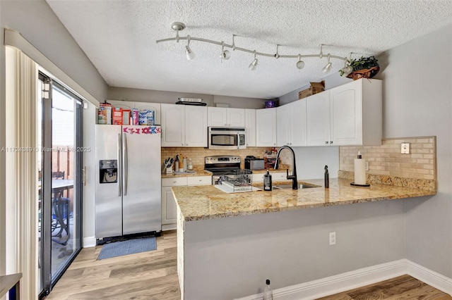 kitchen with kitchen peninsula, sink, white cabinets, and appliances with stainless steel finishes