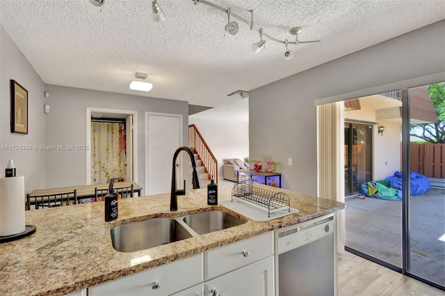 kitchen featuring dishwasher, white cabinets, sink, light hardwood / wood-style flooring, and light stone countertops