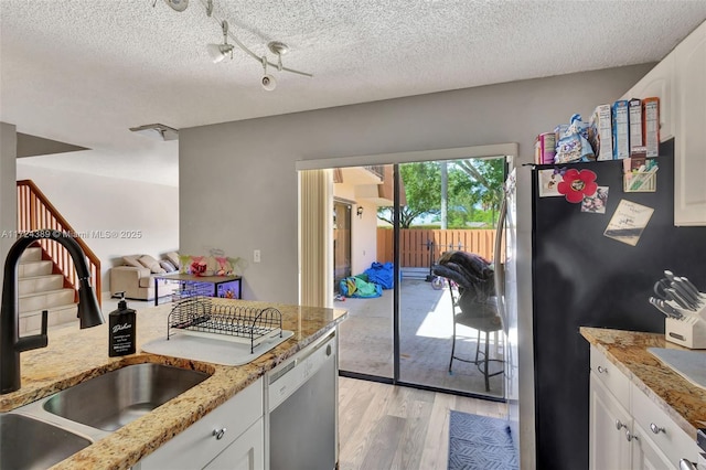 kitchen with light stone countertops, white cabinetry, stainless steel appliances, light hardwood / wood-style flooring, and a textured ceiling