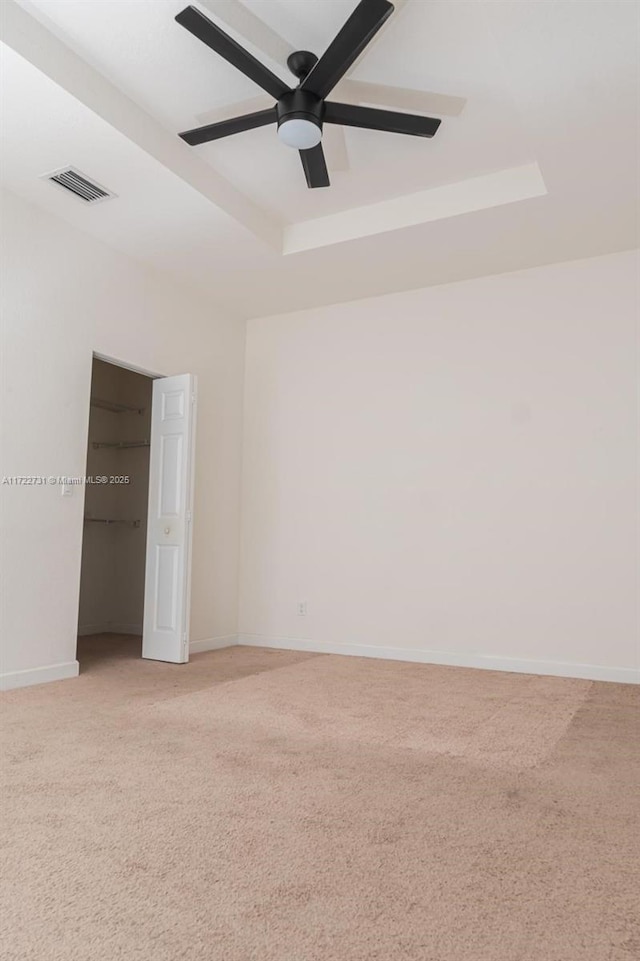 spare room with light colored carpet, a raised ceiling, and ceiling fan