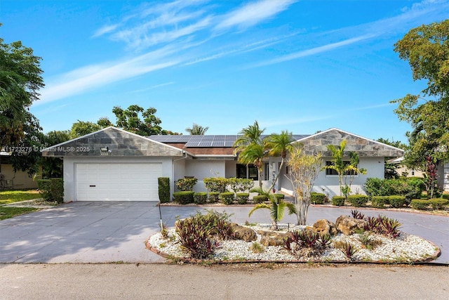 ranch-style home with a garage and solar panels