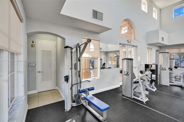 gym with tile patterned flooring and a towering ceiling