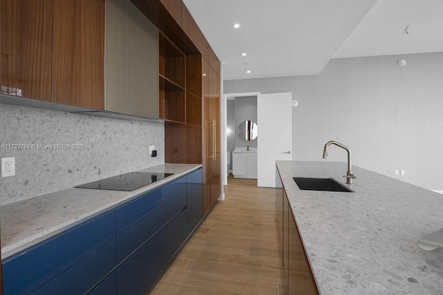 kitchen with sink, tasteful backsplash, wood-type flooring, light stone countertops, and black electric cooktop